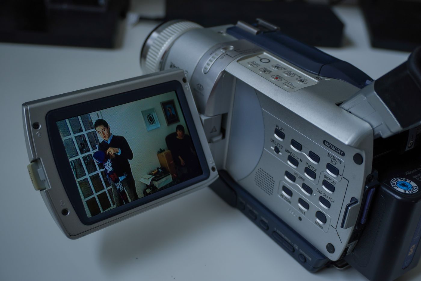 A silver Sony camcorder with its flip-out screen open, playing back home video