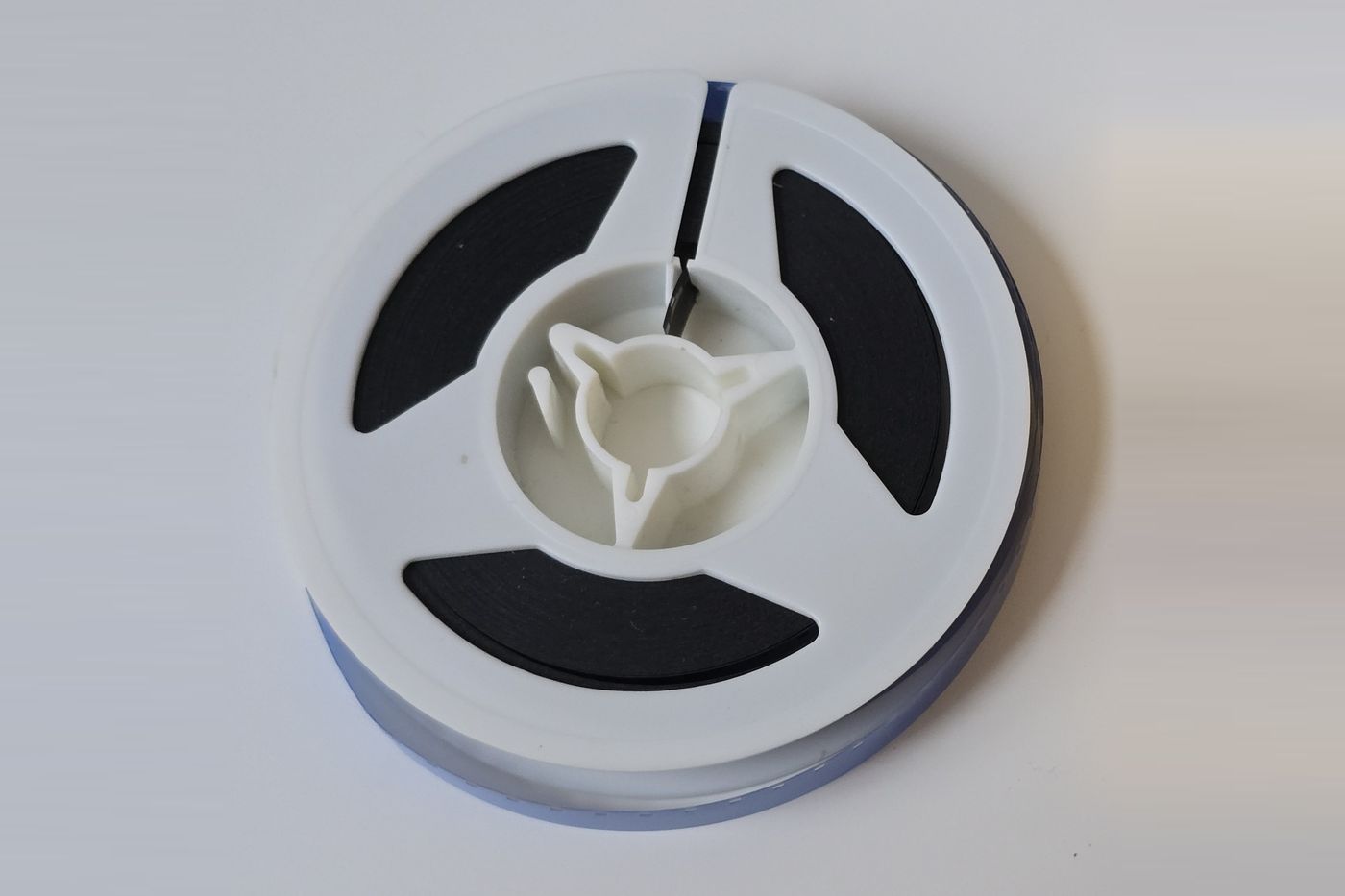 A small white plastic reel of 8mm home movie film