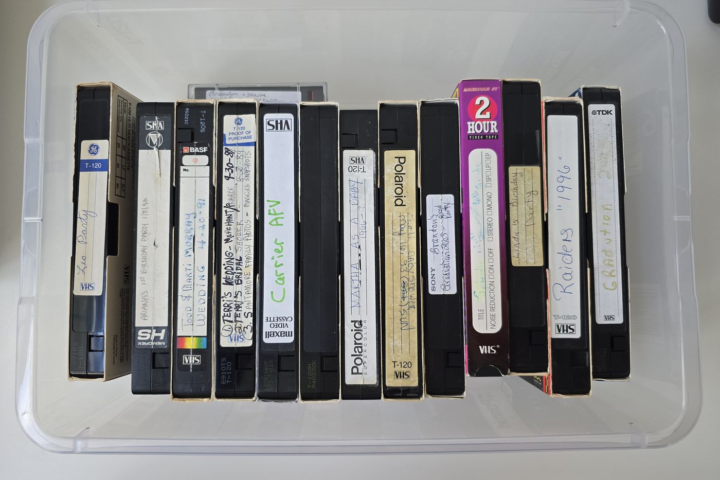 A storage bin full of family VHS tapes with handwritten labels