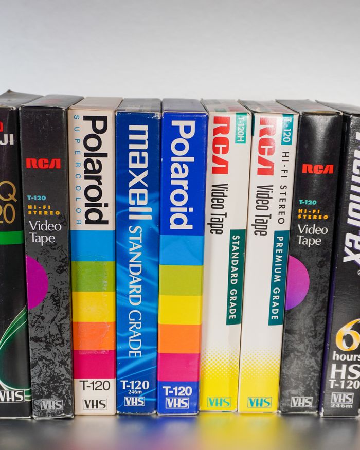 A row of Polaroid, Maxell, RCA and Memorex VHS tapes standing on a shelf